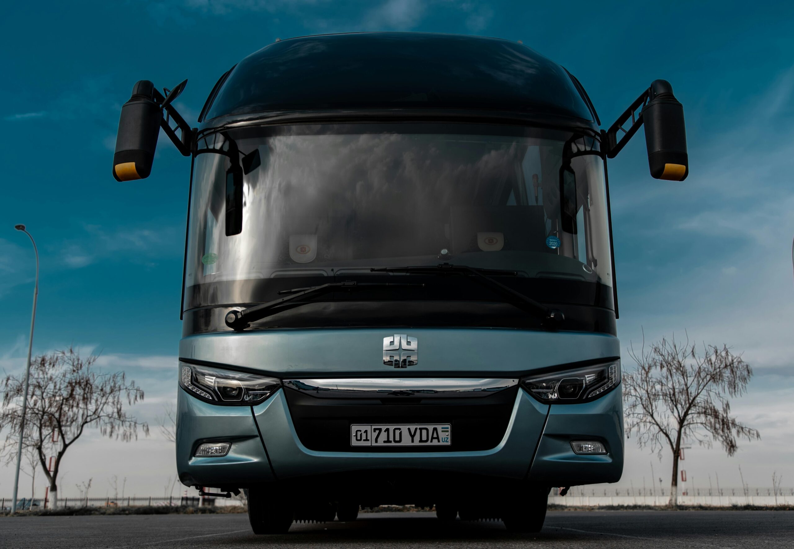 A luxury bus parked near a Norwegian fjord with tourists enjoying reclining seats inside.
