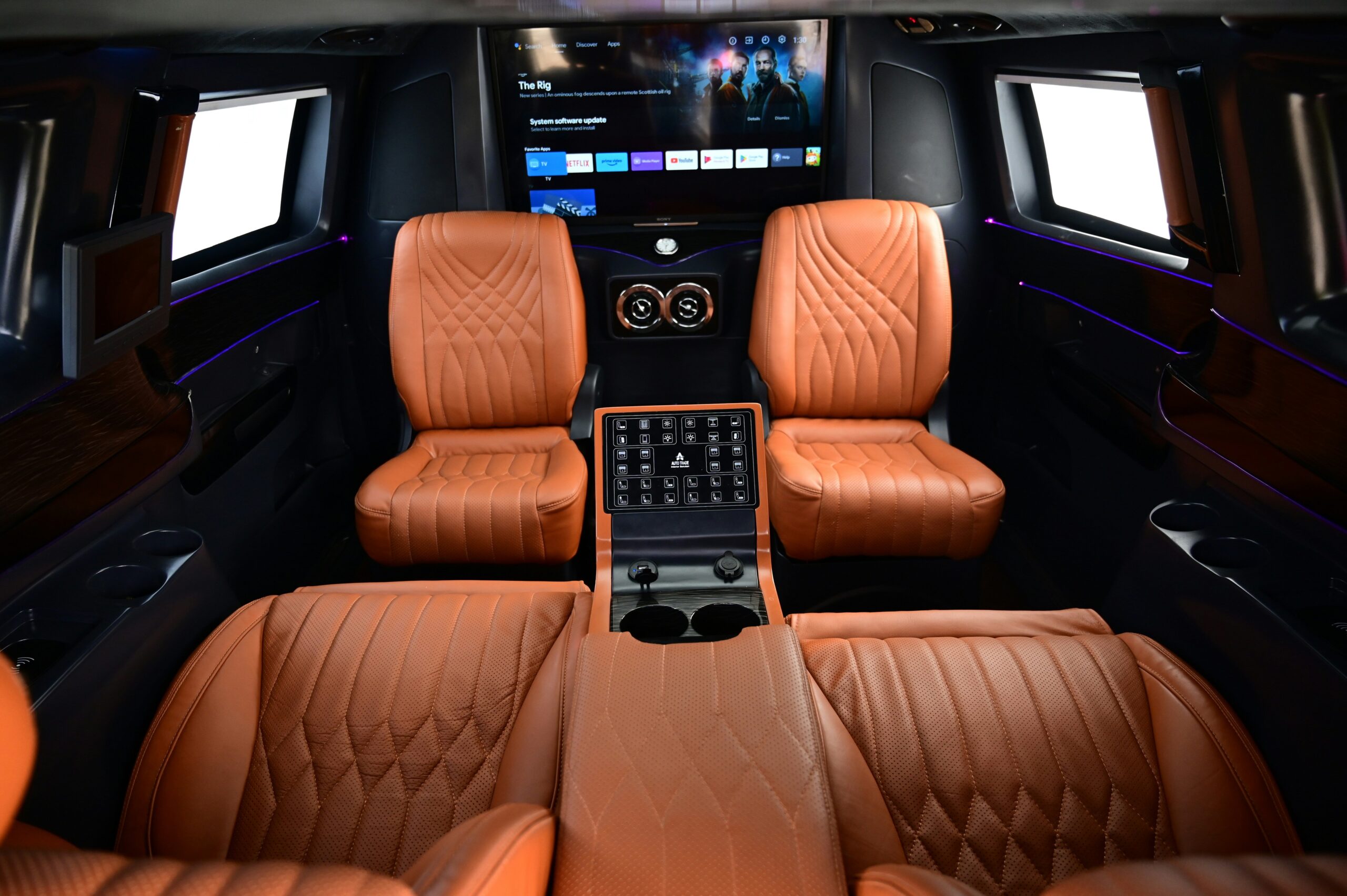 Interior of a modern luxury bus featuring reclining leather seats and ambient lighting