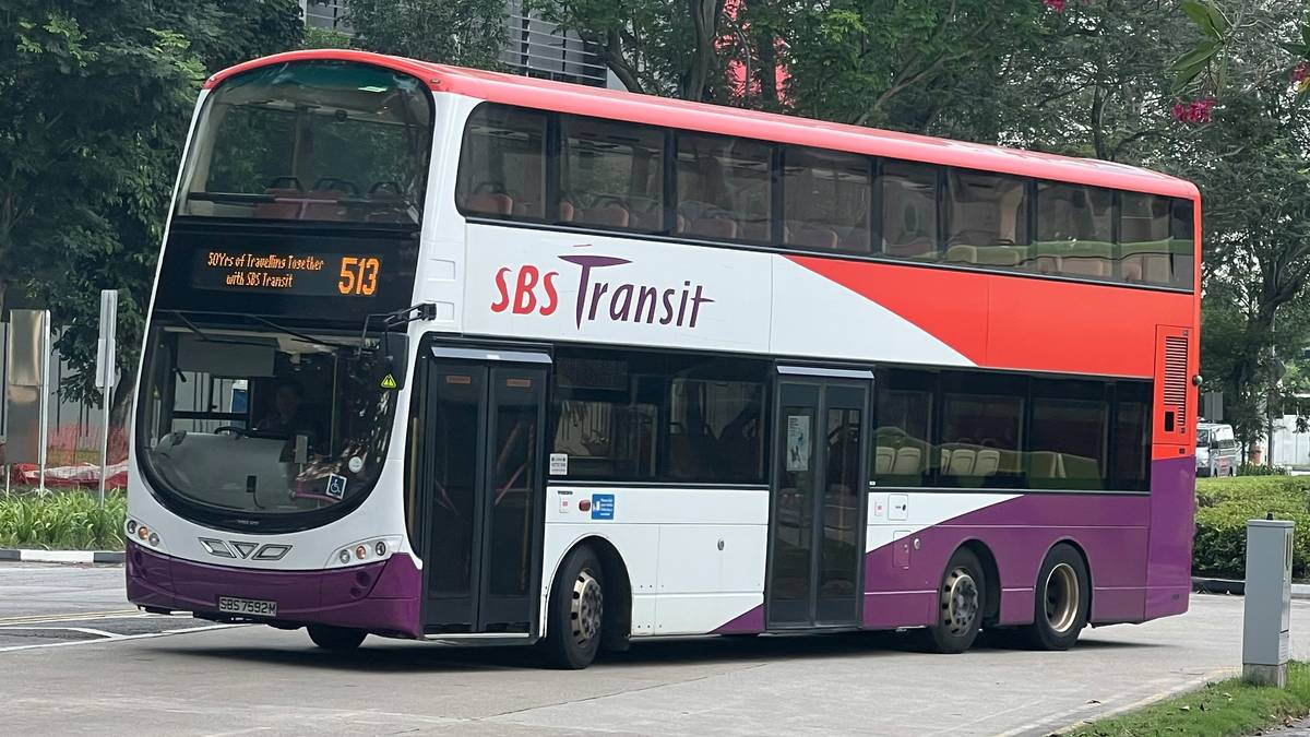 A luxury bus traveling along a winding coastal road surrounded by mountains