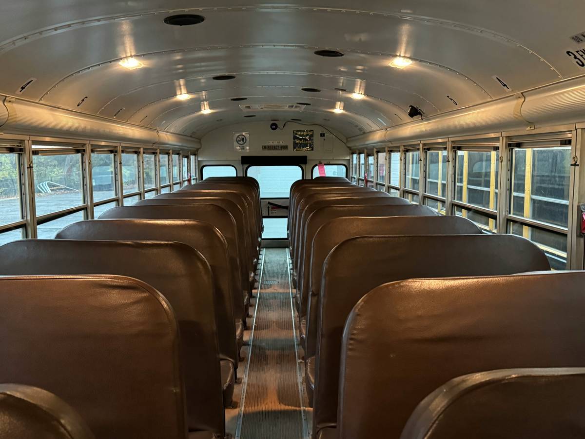 A spacious interior of a luxury bus featuring leather seats and tray tables
