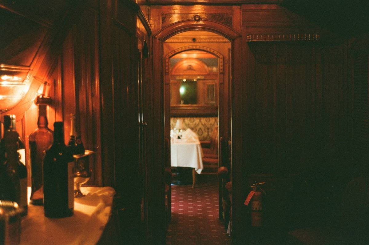 Dark, ornate hallway with bottles and a table.