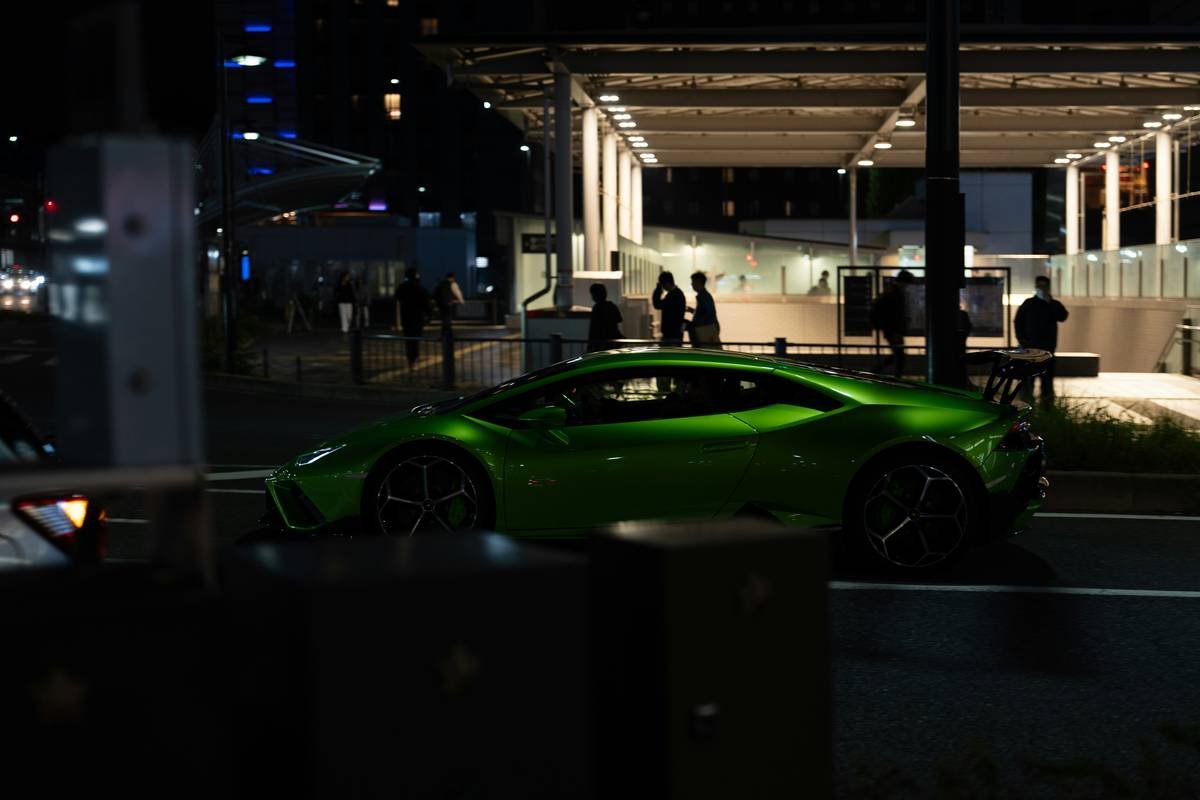 Green sports car driving on a city street at night.