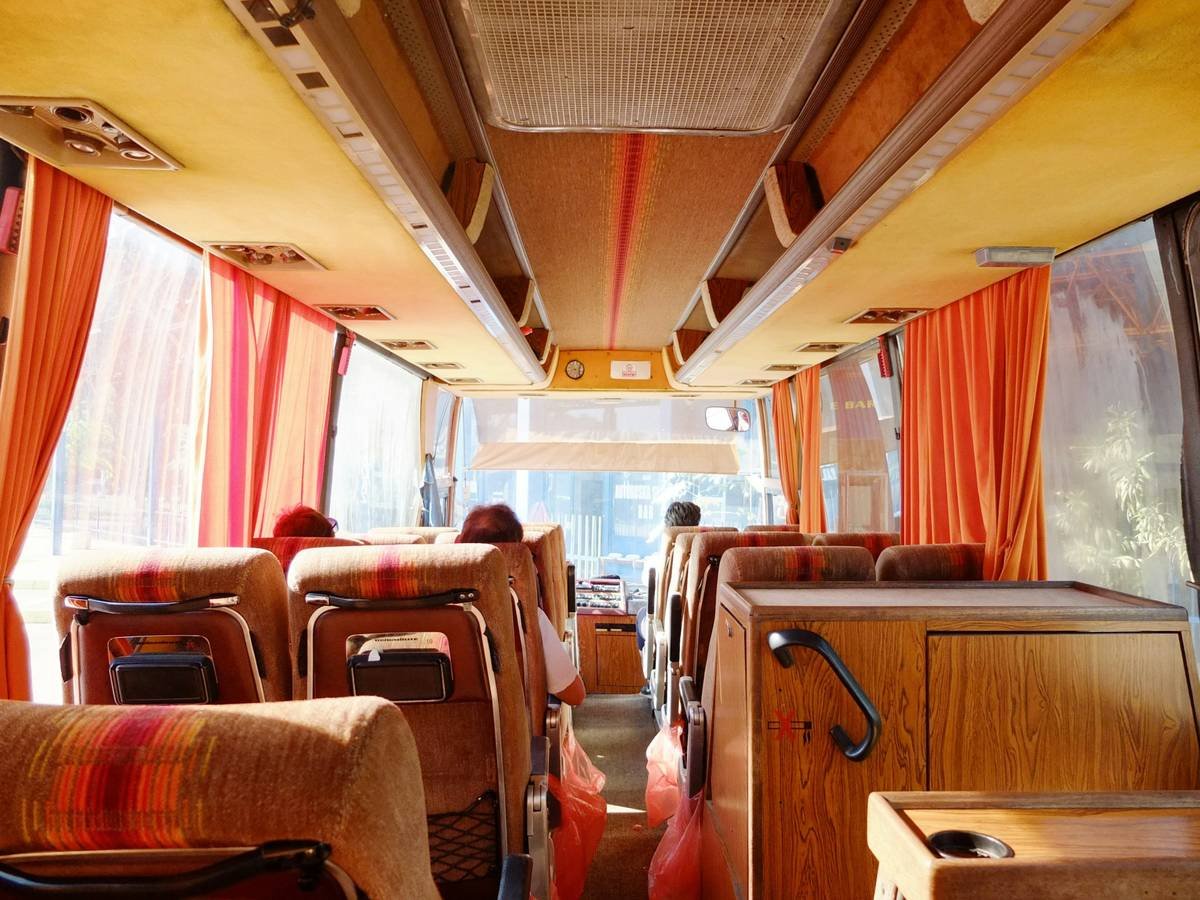 Infographic showing luxury bus amenities: leather seats, restroom, Wi-Fi, panoramic windows, climate control, and professional guide