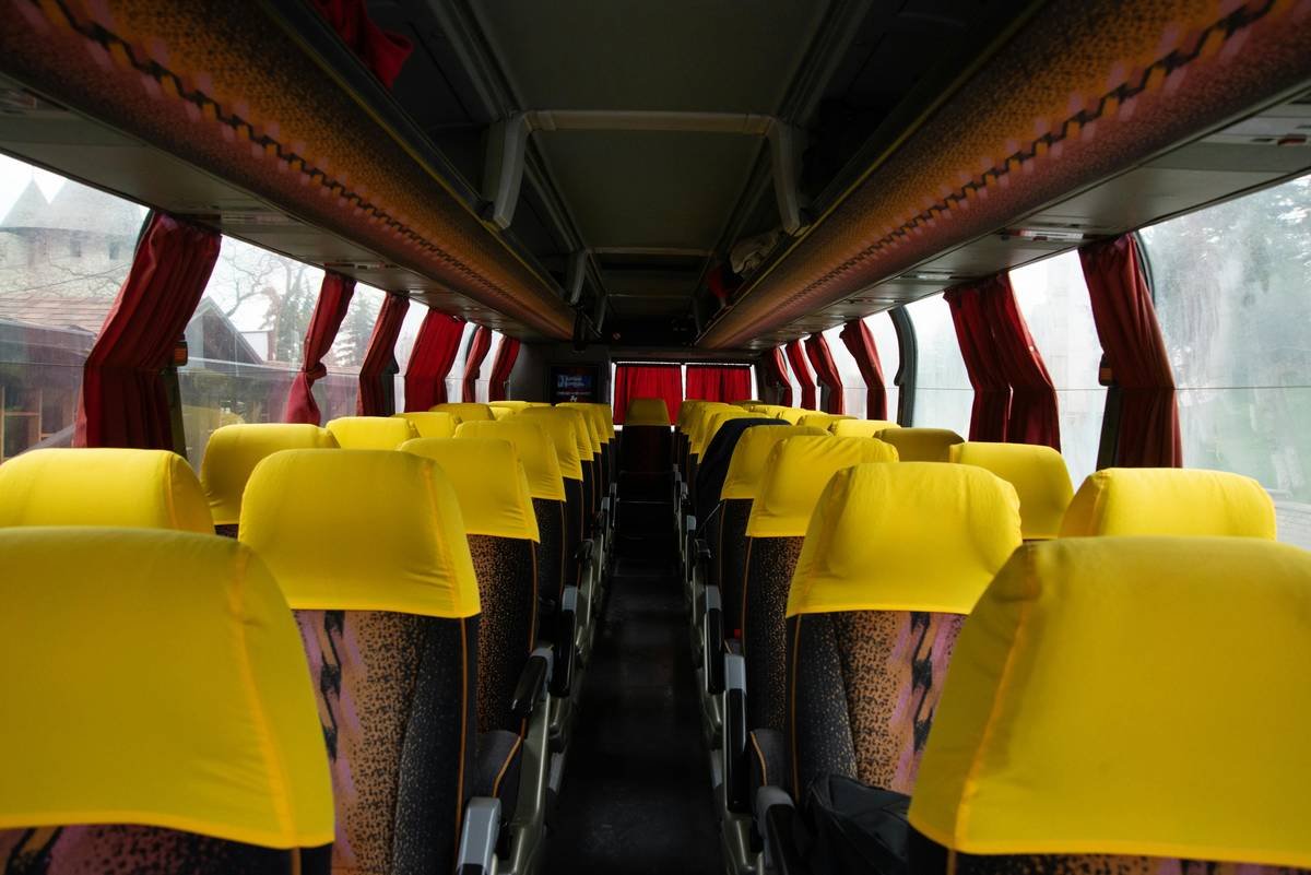Interior of a luxury bus in India showing 1x1 seating, personal screens, mood lighting, and attendant serving refreshments