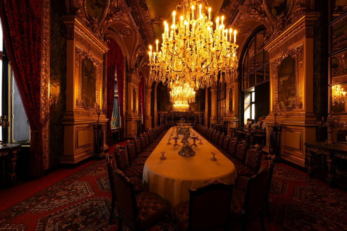 Ornate dining hall with long table and chandeliers