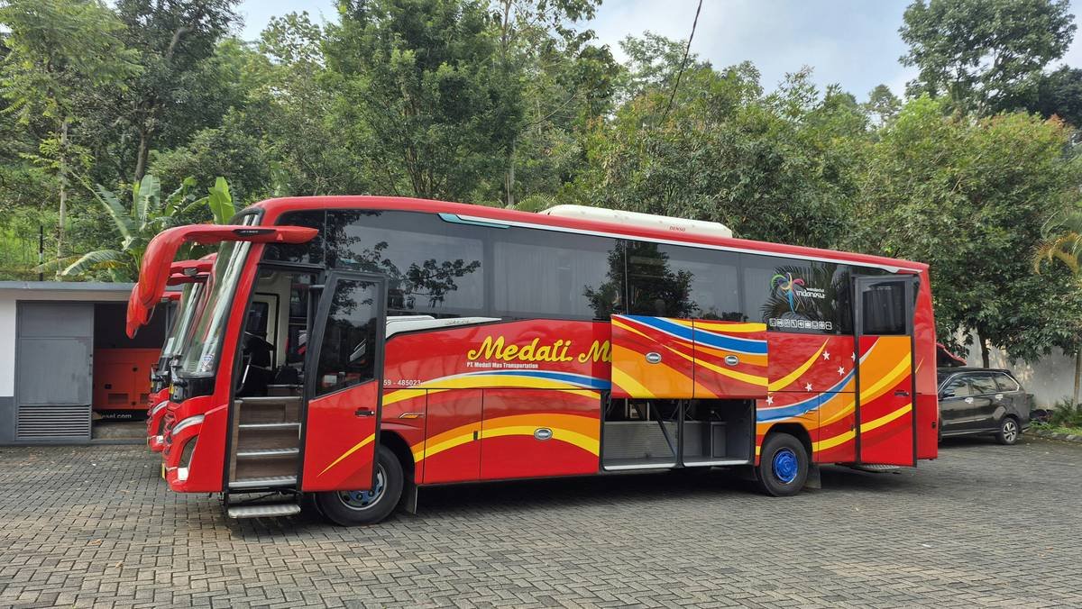 Red "medali mas" bus with open door and colorful designs.