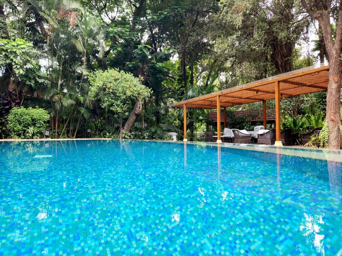 The luxurious tropical themed outdoor swimming pool and spa at the Taj West End Hotel, Bangalore, Karnataka, India. Nestled amidst 20 acres of flora and defined by its illustrious heritage and colonial charm, Taj West End, Bengaluru is a lush sanctuary in Bengaluru. Started by the Bronsons as a 10-room inn in 1887, it now has 117 magnificent rooms and suites that dot the sprawling landscaped gardens, each with a gorgeous view.