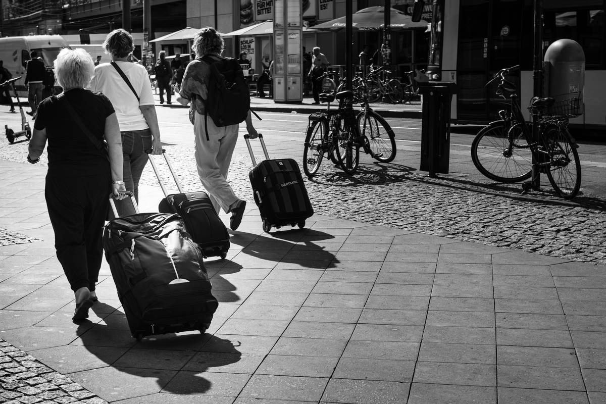 Three people are leaving carrying their trolleys