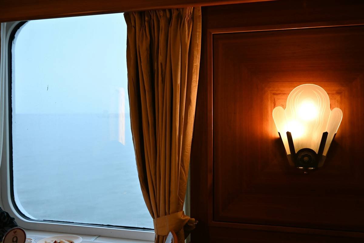 Window view of ocean next to lit wall sconce