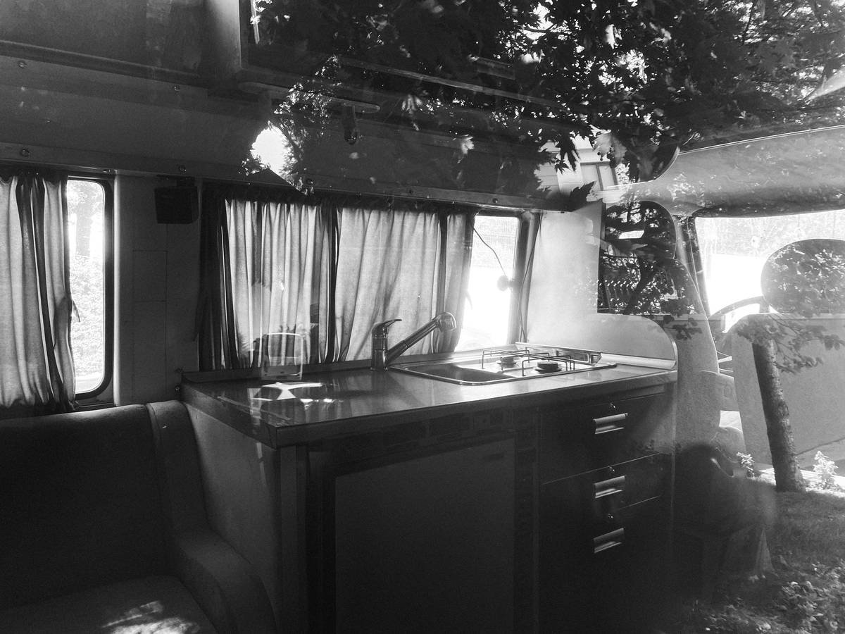 a black and white photo of a kitchen in a bus