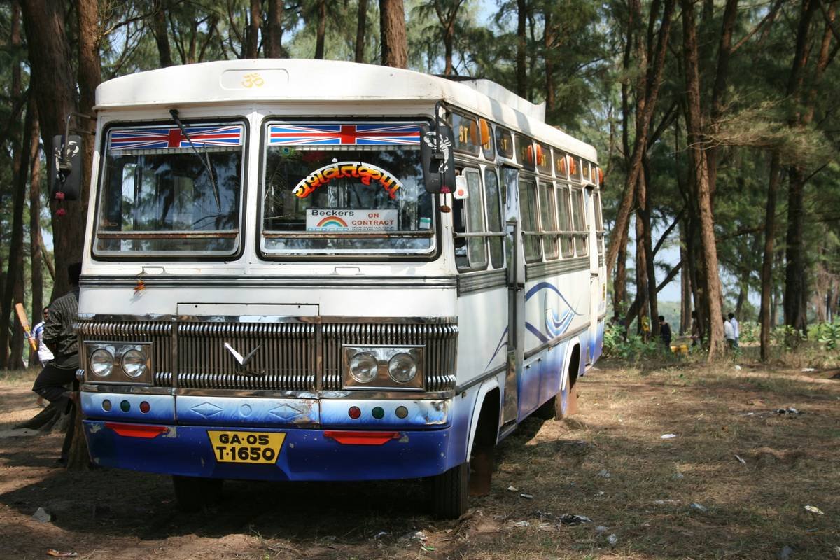 Interior of a luxury tourist bus in Kerala showing reclining leather seats, ambient lighting, and onboard restroom door