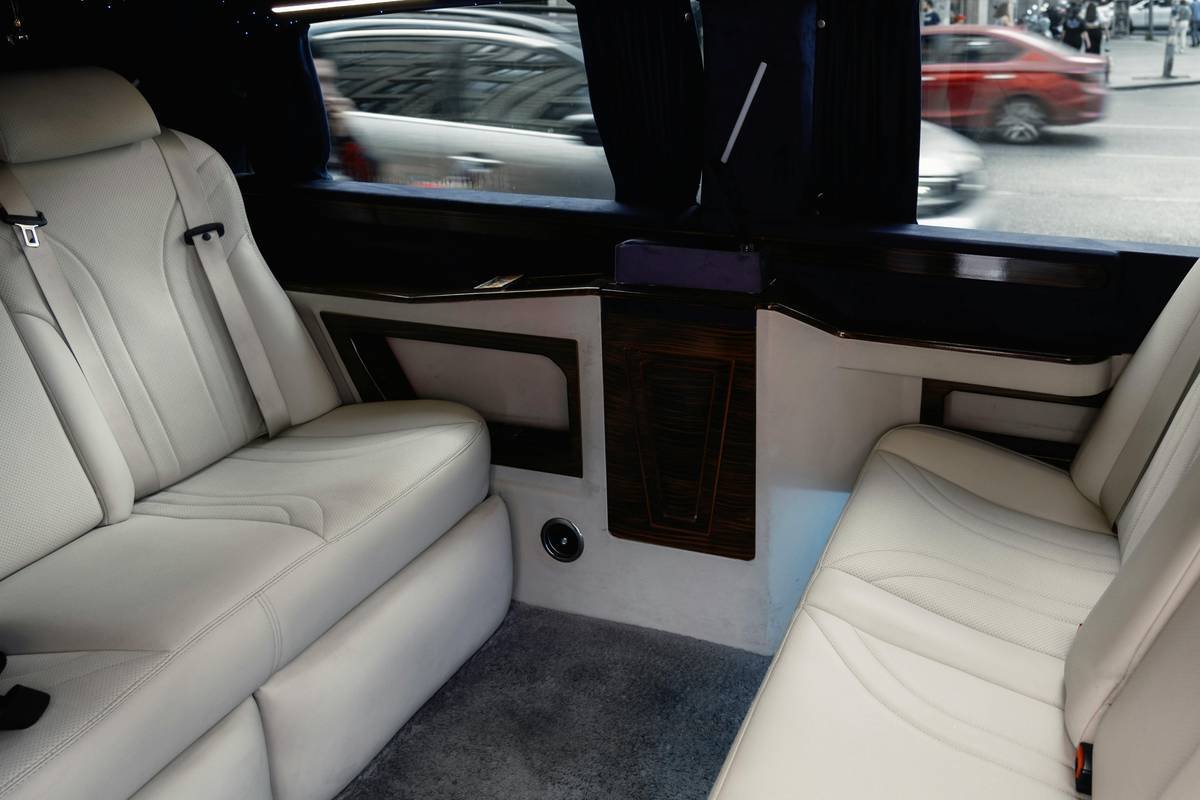 Interior of a modern first class bus showing lie-flat leather seats, panoramic windows, and mood lighting