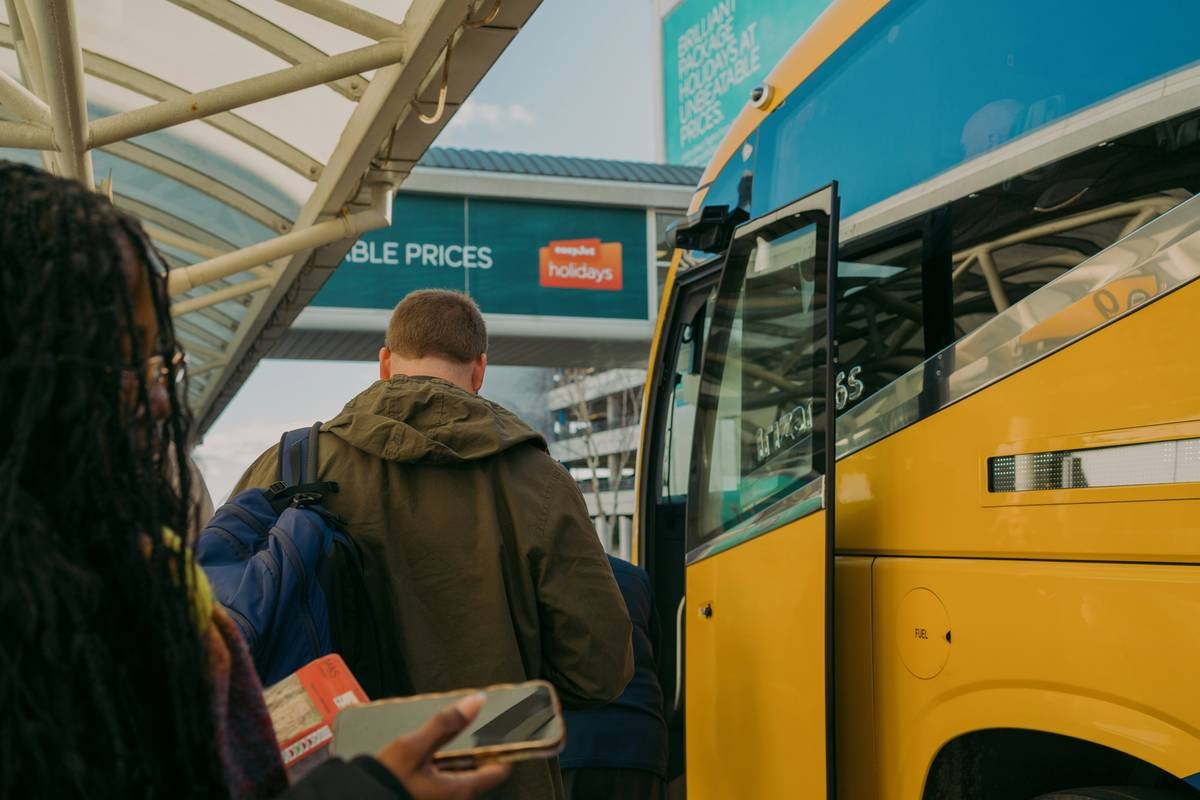 Happy students boarding a clean, modern student first school bus at dawn